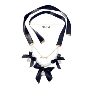 Detailed view of European vintage black ribbon pearl necklace with crystal bows and love pendant.