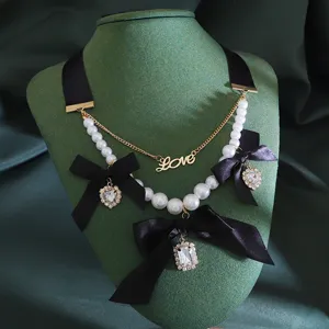 Vintage black bow pearl choker necklace with rhinestone pendant and love letter detail.