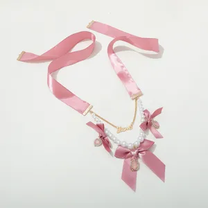 Pink ribbon pearl necklace detail view, sweet bow and rhinestone pendant design.