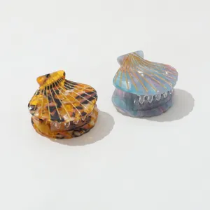 Gedetailleerd overzicht van twee elegante schelpvormige acetaat haarklemmen in blauw.