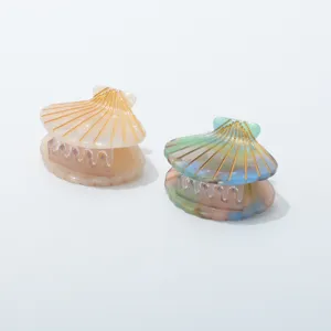 Detailopname van schelp haarclips van acetaat met goudetails voor dagelijks gebruik.