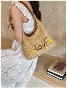 Dettaglio della borsa a spalla in paglia intrecciata con lettere LOVEX ricamate e tema marino.