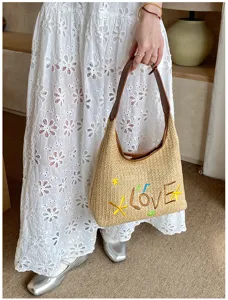 Borsa a tracolla intrecciata da spiaggia estiva, vista dettagliata della paglia e ricamo LOVE.