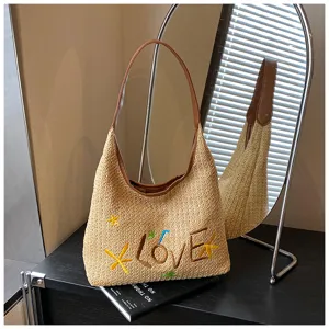Borsa a spalla estiva in paglia intrecciata con lettere d'amore ricamate e dettagli in pelle.