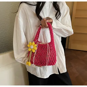 Fashionable candy pink woven mesh handbag for women, chic hollow design with yellow flower pendant.