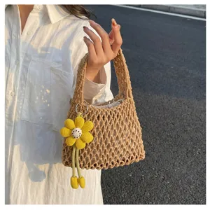 Detail view of a stylish beige woven net handbag featuring a cute yellow flower charm accessory.