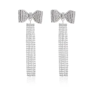 Close-up of silver rhinestone bow tassel earrings detail, sparkling luxury fashion design.