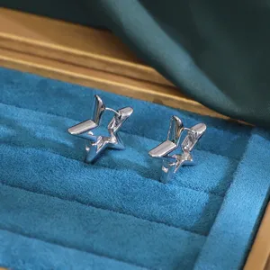 Close-up detail of silver star hoop earrings in blue velvet jewelry box, minimalist alloy design.