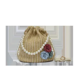 Detail view of the woven straw bucket bag featuring elegant pearl handle and colorful flowers.