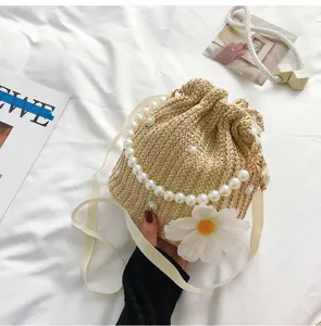 Chic woven straw bucket bag with elegant pearl chain and daisy for summer vacation.