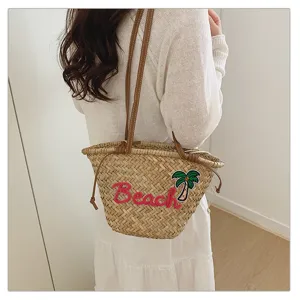 Élégant sac de plage en paille tressée avec anses en cuir et broderie de palmier.