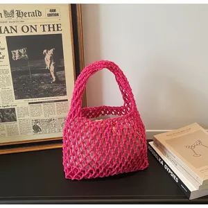 Detailed shot of a hot pink woven hollow net handbag with beige lining, perfect for beach style.