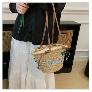 Vue détaillée du sac cabas en paille tissée avec broderie de plage et lanières marron.