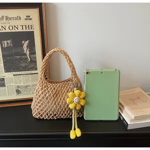 Detailed shot of casual khaki woven mesh handbag with cute yellow flower charm for summer beach.