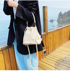 Chic straw woven bucket bag with pearl chain strap and sweet daisy flower for resort beach style.