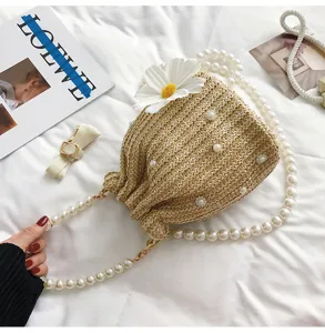 Straw bucket bag detail with pearl strap and white flower decor, perfect for summer beach style.