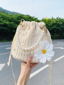 Straw bucket bag with pearl chain handle and large white daisy flower for beach vacation.