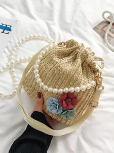 Resort style straw bucket bag with pearl chain handle and floral decoration for beach vacation