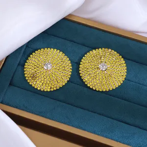 Close-up van retro overdreven ronde strass oorbellen met levendige gele kristallen.