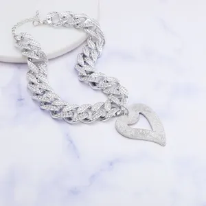 Close-up detail of the chunky rhinestone cuban chain necklace with a hollow heart pendant.