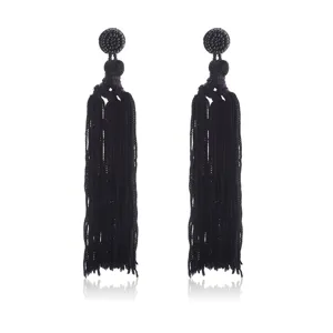 Zwarte kwast oorbellen detail opname, handgemaakte kraal hangende sieraden close up boho stijl.