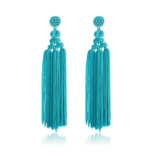 Gedetailleerde close-up van handgemaakte turquoise kwast-oorhangers, boheems geweven kralenontwerp.