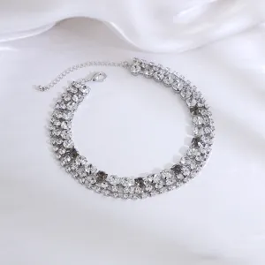 Close up detail of multi row sparkling crystal rhinestone choker necklace on soft white satin.