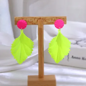 Neon groene bladoorbellen met felroze ronde knopjes, stijlvolle geometrische sieraden.