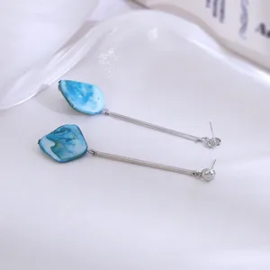Detail van lange oorbellen met blauwe natuursteen en zilverkleurige metalen stang dames.
