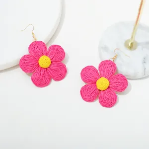 Handgemaakte raffia bloem oorbellen detailweergave, boho stijl roze en gele sieraden close-up.