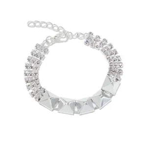 Gedetailleerde close-up van een stijlvolle zilveren strass- en metalen klinknagelarmband.