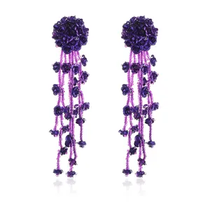 Close-up detail shot of elegant purple beaded flower tassel earrings, intricate metal design.