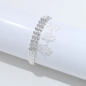 Gedetailleerde close-up van een zilverkleurige, meerstrengs strass armband met fijne Hamsa bedels.