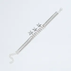 Close-up detail van een zilverkleurige strass-armband met dubbele rij en drie sterren.