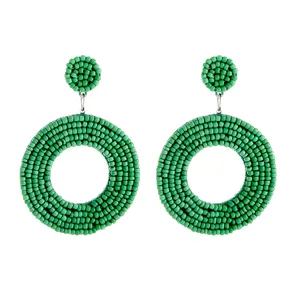 Close-up detail of handmade green seed bead circular earrings showing exquisite weaving texture.