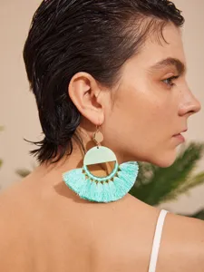 Detailopname van boheemse turquoise kwastje oorbellen gedragen door model, elegant design.