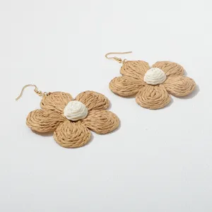 Close-up van handgemaakte gevlochten raffia bloemoorbellen met bruine bloemblaadjes.