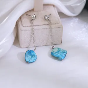 Lange ketting oorknopjes met blauwe schelp hangers, elegante minimalistische vakantie stijl.