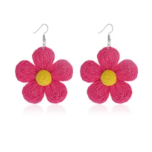 Handgemaakte raffia bloem oorbellen detail, levendig roze bloemblaadjes en gele kern, chique.