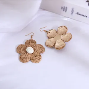Gedetailleerde close-up van handgeweven rafia en metalen bloemoorringen, boho vakantiestijl.