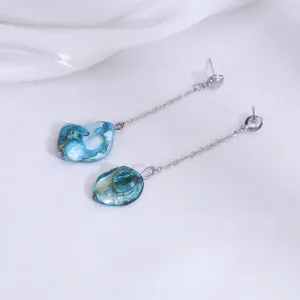 Close-up detailweergave van lange ketting oorbellen met onregelmatige blauwe stenen.