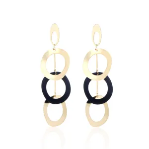 Gedetailleerd overzicht van trendy geometrische lange oorbellen met gouden en zwarte ringen.