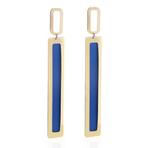 Detail view of long geometric metal dangling earrings with gold finish and blue enamel insert.