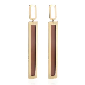 Detailed view of long geometric drop earrings featuring a gold frame and brown panel design.