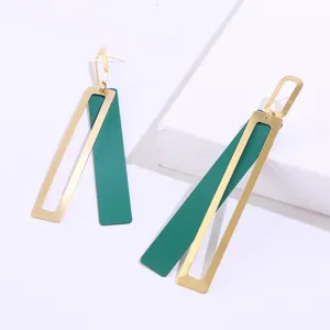 Detailed view of long geometric earrings with gold frame and green rectangular pendant.