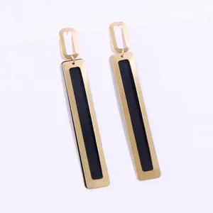Close up of geometric long gold metal dangle earrings with elegant black inner design.