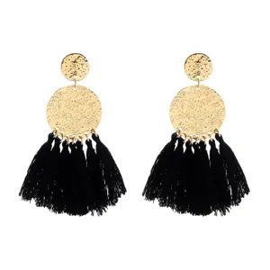 Detail shot of gold textured disc and black tassel boho earrings showcasing craftsmanship.
