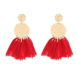 Detailed view of bohemian style long red tassel earrings with hammered gold metal discs.
