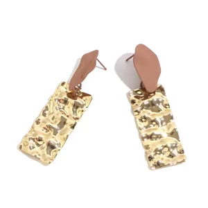 Detailed view of creative long earrings with matte top studs and textured gold rectangular pendants.