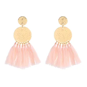 Detailed close-up view of bohemian pink tassel earrings featuring textured gold metal round discs.